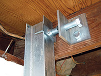 Securing the i-beam system to the top of the floor joist in a foundation wall repair in Allison Park.